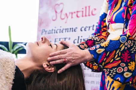 Mains de la praticienne réalisant un soin Nursing Touch sur une personne allongée